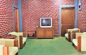 Villa Orange Lembang Pengkolan في ليمبانغ: غرفة معيشة مع تلفزيون وجدار من الطوب