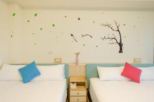 a bedroom with two beds with green leaves on the wall at 鴻滿億民宿 in Magong