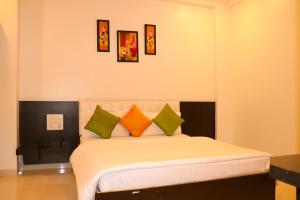 a bedroom with a bed with orange and green pillows at Hotel Neem Tree in Shirdi
