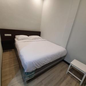 een klein bed in een kleine kamer met witte lakens bij Circle One in Palembang