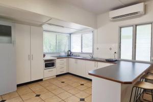 uma cozinha com armários brancos e um balcão preto em Island Bungalow em Bongaree