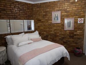 a bedroom with a white bed with a brick wall at Troas Boutique hotel in Vanderbijlpark