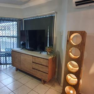 a living room with a tv and a dresser at Villa Venezia Apt 3 - Spacious Hervey Bay beachfront apartment in Hervey Bay