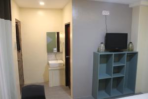 Habitación con TV en un estante y baño. en NINIE'S PLACE en Puerto Princesa