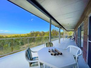 een veranda met een witte tafel en stoelen op een balkon bij Treetops in Agnes Water