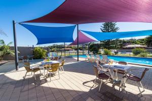 a patio area with chairs, tables and umbrellas at ibis Styles Geraldton in Geraldton