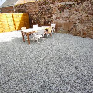 a wooden table and chairs on a gravel patio at Le pont T3 étoilé avec jacuzzi in Saint-Méloir-des-Ondes