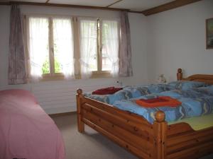 Schlafzimmer mit einem Bett mit blauer Bettwäsche und Fenstern in der Unterkunft Chalet uf em Stutz 1 in Grindelwald