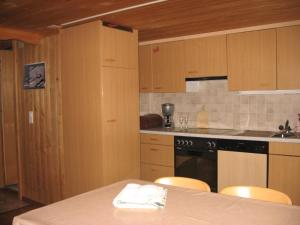 una cocina con armarios de madera y una mesa con sillas. en Chalet uf em Stutz 1, en Grindelwald