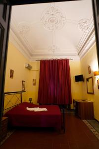 Hotel Etnea في كاتانيا: غرفة نوم بسرير احمر وستارة حمراء