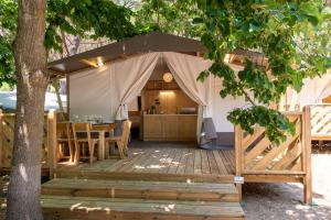 een tent met een tafel en stoelen op een houten terras bij Camping Village Santapomata in Castiglione della Pescaia