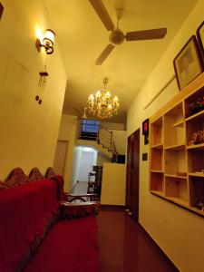 a living room with a red couch and a chandelier at Calvin's Inn in Cochin