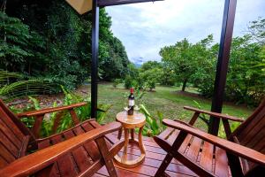 a porch with two benches and a table with a bottle on it at Cape Trib Farm in Cape Tribulation +7 photos