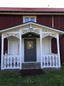 a white front porch of a red house with a door at Fråsttorp in Aneby