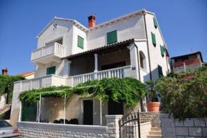a large white house with a balcony on a street at Garden apartment with a View in Postira