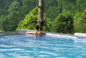 a man in a swimming pool with a tree at Blue Pine Resort in Lansdowne