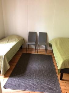 2 Betten und 2 Stühle in einem Zimmer mit einem Teppich in der Unterkunft Lupiini in Savonlinna