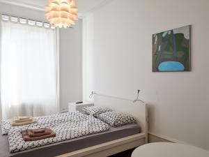 a white bedroom with a bed and a chandelier at Apartments Spalenring 10 in Basel