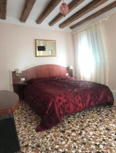 1 dormitorio con 1 cama grande de color rojo y ventana en B&B a le Boteghe en Venecia