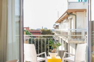 a balcony with white chairs and a plant at Hotel Mediterraneo in Sottomarina