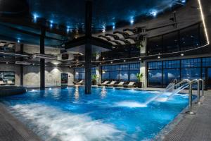 duży basen z niebieską wodą w budynku w obiekcie Hotel Seidorf w Sosnówce koło Karpacza w mieście Sosnówka