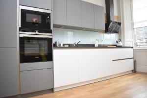 uma cozinha branca com armários brancos e um micro-ondas em Bernard St - Bright and spacious 1 bed apartment at the Shore! em Edinburgo