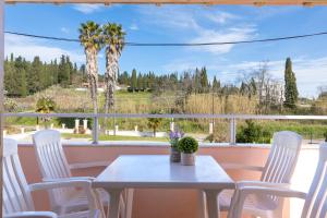 a table and chairs on a balcony with a large window at Nikos Pool House & Apartments in Sidari