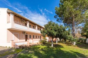 a large white building with trees in the yard at Nikos Pool House & Apartments in Sidari