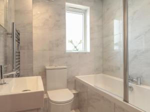a bathroom with a toilet and a tub and a sink at Harbourside Haven Apartment 1 in Weymouth +10 photos