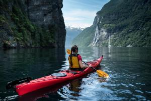 a woman in a red kayak in the water at Hotel Union Geiranger Bad & Spa in Geiranger