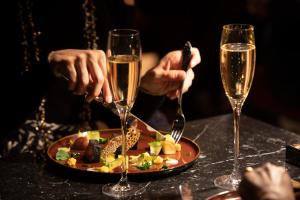2 personnes avec des verres de champagne et une assiette de nourriture dans l'établissement Paris j'Adore Hotel & Spa, à Paris