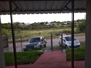 dwa samochody zaparkowane na parkingu obok ogrodzenia w obiekcie La Comarca w mieście Colonia del Sacramento