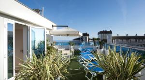 a balcony with chairs and an umbrella on a building at Hotel Tropical in Lido di Jesolo