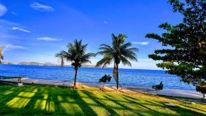 a view of a beach with palm trees and the ocean at Pousada Algodão da Praia in Araruama