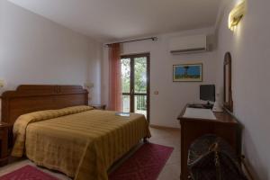 een slaapkamer met een bed en een bureau met een computer bij Hotel Ispinigoli in Dorgali
