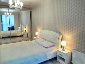 um quarto com uma cama branca e um espelho grande em СУЧАСНА НОВА КВАРТИРА em Lutsʼk