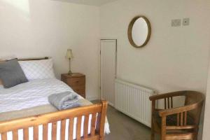 a bedroom with a bed and a mirror and a chair at Horsemans Barn in Kingsbridge