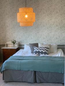 ein Schlafzimmer mit einem Bett mit orangefarbenem Licht darüber in der Unterkunft Rosenfors Herrgård B&B in Borgholm