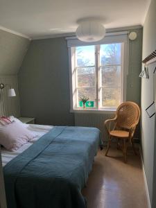 1 dormitorio con cama, ventana y silla en Rosenfors Herrgård B&B, en Borgholm
