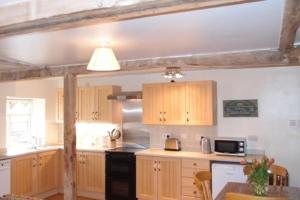 a kitchen with wooden cabinets and a black stove at Upper Heath Farm - Stable Cottage in Craven Arms