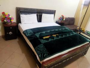 a bed with a black and green blanket on it at New Hajveri Hotel Lahore in Lahore