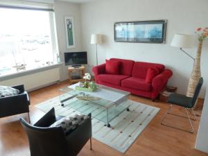 een woonkamer met een rode bank en een tafel bij Appartement "Zicht op de Vuurtoren" in Noordwijk aan Zee