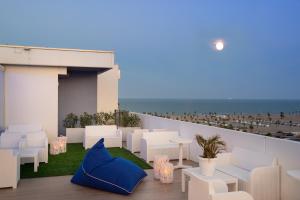 a balcony with white chairs and tables and the ocean at Hotel Mediterraneo in Sottomarina