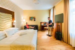 un hombre de pie en una habitación de hotel con dos camas en Hotel Josefshof am Rathaus en Viena