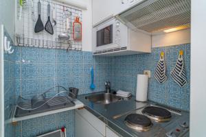 a small kitchen with blue tiled walls and a sink at App. Seestr. 6d in Wenningstedt