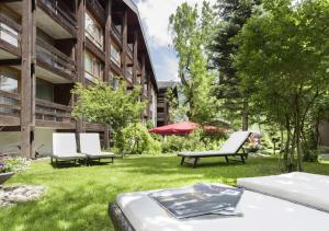 einen Hof mit zwei weißen Stühlen und einem Gebäude in der Unterkunft Hotel Kreuz Lenk in Lenk im Simmental