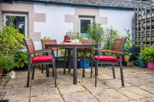 einen Tisch und vier Stühle vor einem Haus in der Unterkunft Dower House Newtonmore B&B in Newtonmore