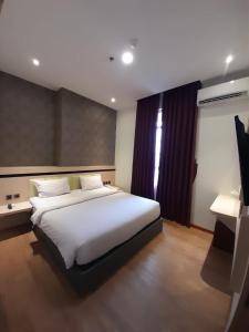 a bedroom with a large white bed and a desk at Blitz Hotel Batam Centre in Batam Center