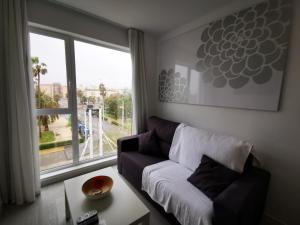 a living room with a couch and a large window at Sol Playa Suites in Valencia