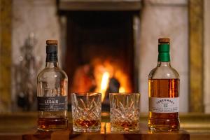 two bottles of whiskey and two glasses on a table at Western Isles Hotel in Tobermory